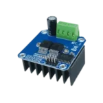 High-power blue HW-039 motor driver board showing a massive black aluminum cooling fins block fixed underneath, an integrated 4-position green terminal block alongside an electro-filtering capacitor, two prominent central half-bridge ICs, and an 8-pin control connector logic bank.