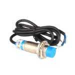 M18 cylindrical inductive proximity sensor showcasing a solid, silver-colored threaded metal casing, a distinct blue plastic sensing head, dual metallic nuts, and a thick black three-conductor output cable.