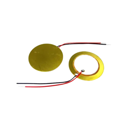 Circular 20mm piezoelectric element disc displaying its gold-colored flat brass base ring supporting a concentric inner circle coated in a matte white ceramic composition layer.