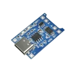 Compact blue TP4056 lithium battery charger board showing a surface-mount Type-C USB input port, twin status indicator LEDs, a main TP4056 charger IC alongside a small DW01A protection chip, and clearly labeled soldering pads for input power, battery terminals, and load output.